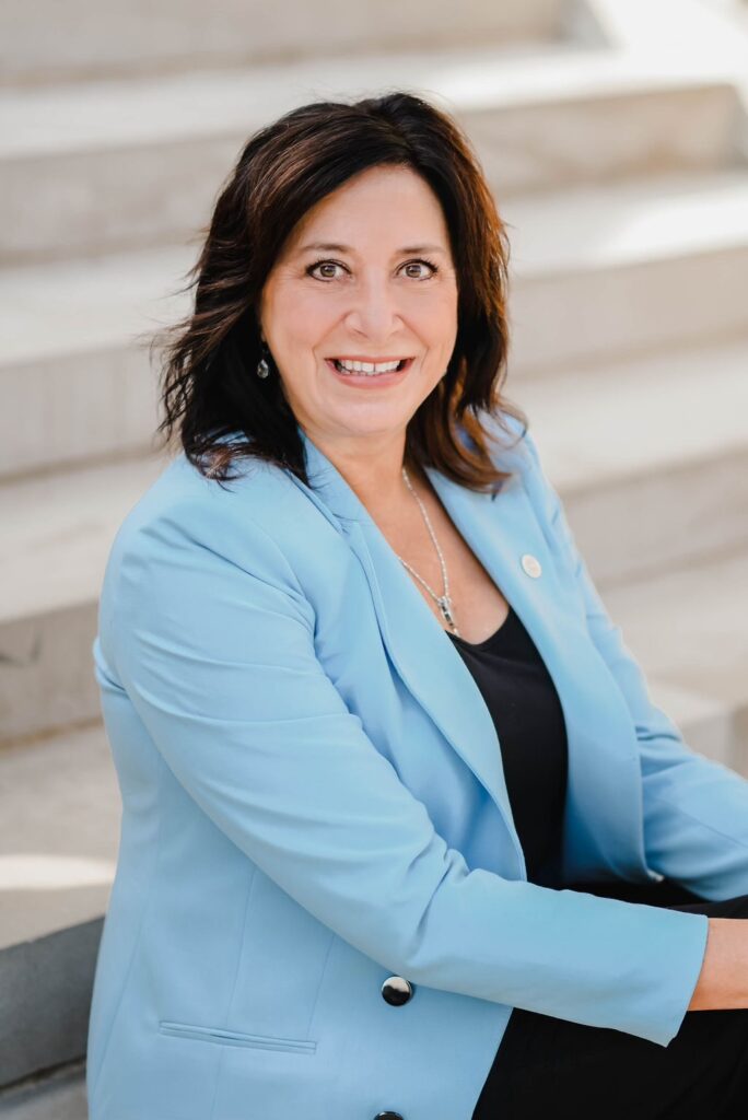 Angela wearing a blue blazer and smiling at the camera.